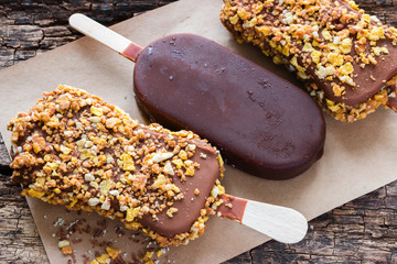 ice cream with chocolate and nuts on a paper on the wooden background closeup