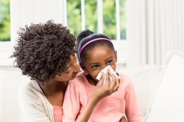 Mother helping daughter blowing her nose