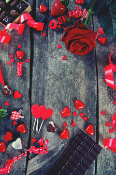 hearts, chocolate, flowers and ribbons on wooden surface