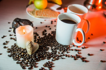 still life of mugs of coffee, coffee beans, and hearts of wood horizontal  in evening  tones