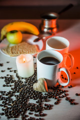 horizontal still life of mugs of coffee, coffee beans, and hearts of wood in warm tones