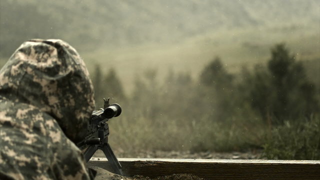 Super slow motion shot of soldier shooting chain gun; training at firing range.