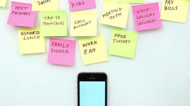 Office desk with smart phone, post it papers and different handwritten notes