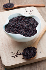 Violet rice grains organic in the wooden spoon on a cutting boar