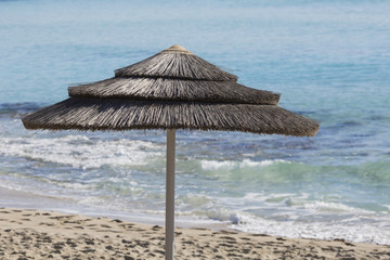 Detail of woven umbrellas above rows on beach in Cyprus.