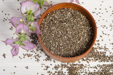 Chia seed healthy super food with flower over white wood backgro