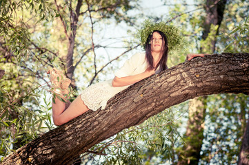 Beautiful woman lying  on tree in forest.