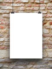 Close-up of one hanged paper sheet frame with clips on medieval brick wall background