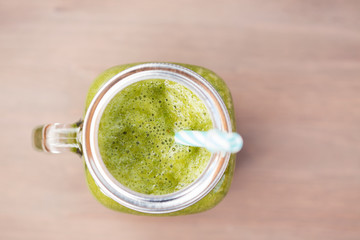 A green smoothie in a mason jar with tube 