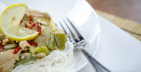 Closeup view of a bowl of thai green curry and rice vermicelli n