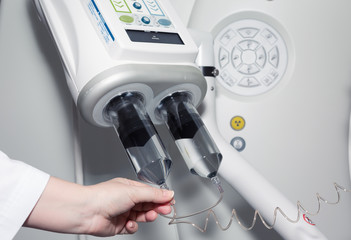 A female doctor's hand on contrast injector