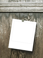 Close-up of one hanged polaroid frame with pin on wooden door background