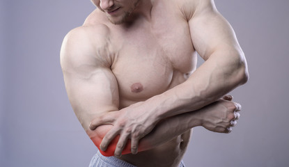 Athletic muscular man has pain in the elbow. Red spot of injury