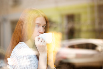 Woman drinking coffee and looking at window