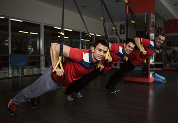 Trx. Gymnastics exercise. Young athletic Caucasian boys training with fitness straps in the gym.