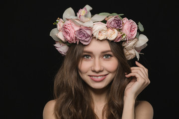Naklejka premium Woman with wreath from flowers on head looking at camera