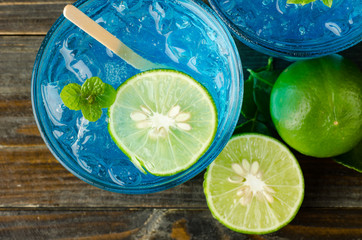 Ice blue drink with lemon on wooden background