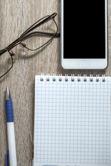  Office desk table with notebooks, pen, smartphone and eye glass