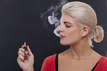Obraz premium Stylish blond woman smoking an e-cigarette