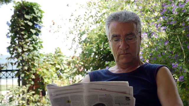 Old retired man reading newspaper 