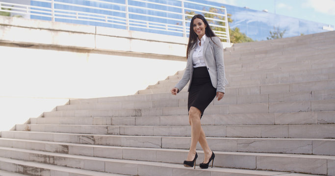 Smiling Young Business Woman In High Heels Walking Down Flight Of Marble Stairs Outdoors