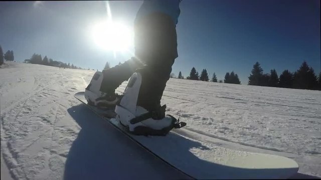 Snowboarder riding down the slope with sun at the background
