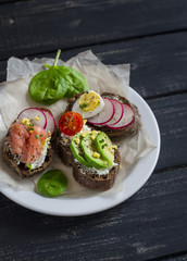 Assortment of sandwiches - sandwiches with cheese, radish, cucumber, quail egg, avocado and smoked salmon. Tasty breakfast, snack or appetizer with wine