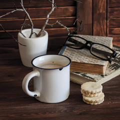 Coffee, biscuits and a stack of old books on brown wooden table. The concept of education and training. Still life in rustic style