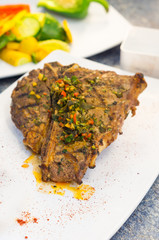Beautifully cooked cutlet with chimichurri topping placed upon white plate, elegant presentation.