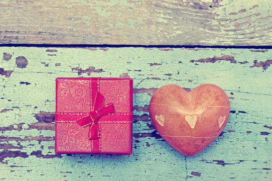 Heart with stones and small gift box with a bow on a wooden background. Greeting card for lovers, friendship or valentine's day.