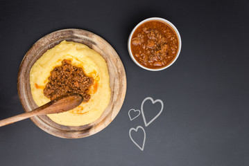 A dish of Polenta with bolognese soup (aka Ragu) standing on a black-board. Some hearts on the blackboard