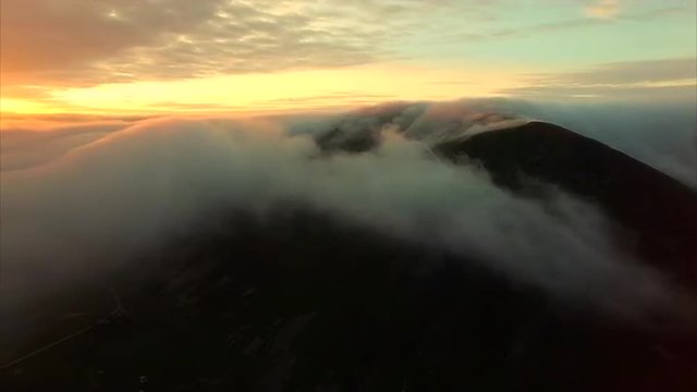 Scenic aerial view of midnight sun with clouds flowing over the mountain peaks on Lofoten islands in Norway. Aerial 4k Ultra HD.