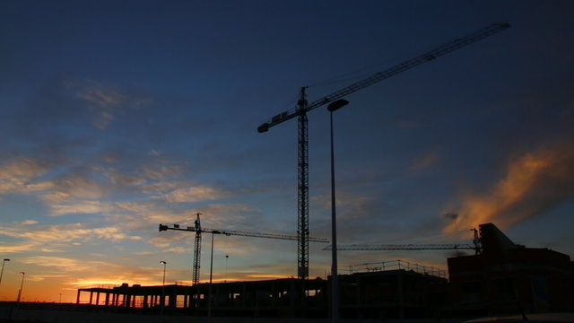Construction cranes at sunset, Construction site, cranes and builders. Time lapse