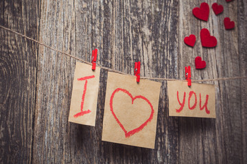 Handwritten words I love you and hearts on wooden background.