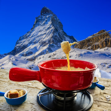 Fondue, traditional Swiss dish - Matterhorn in Swiss Alps in background