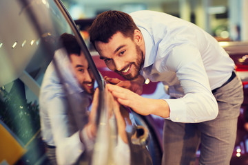 happy man touching car in auto show or salon