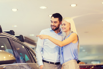 happy couple buying car in auto show or salon