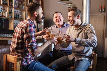 Happy friends drinking beer at counter in pub
