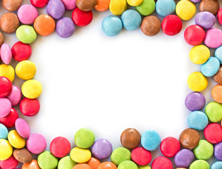 Frame of colorful rounded candies, smarties isolated on white background