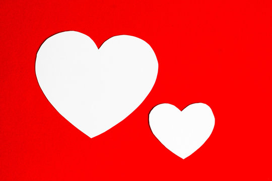Two paper hearts on red background