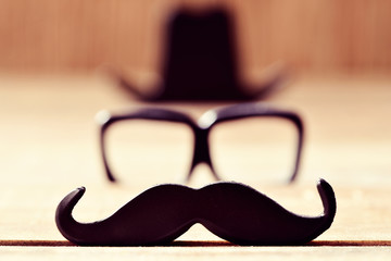 mustache, eyeglasses and hat forming the face of a man