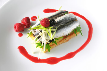 dish of sardines, anchovies, arugula, red berries, cheese and pa