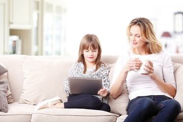Happy mother and daughter with digital tablet