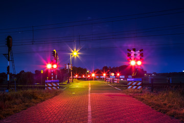 Bewaakte spoorwegovergang met brandende lichten in de nacht 