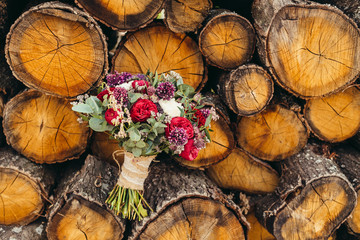 Rustic wedding bouquet with red rose and lilac flowers on wooden