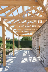 Building house from aerated concrete building blocks. New residential wooden construction home framing against a blue sky