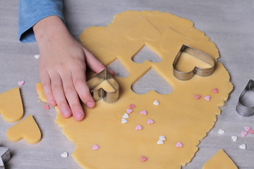 St. valentine's day cookies. Child making heart shaped cookies close up. Surprise present ideas for mother birthday or mother's day. Family concept. Baking with kids