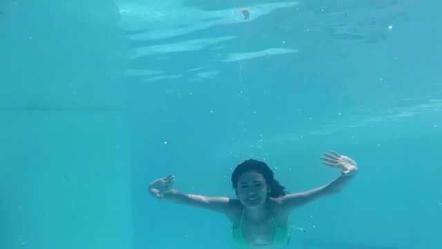 Pretty woman swimming underwater in pool