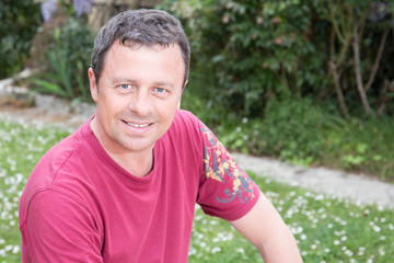 Close-up of a man smiling outside with a pink shirt