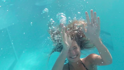 Pretty woman swimming underwater in pool